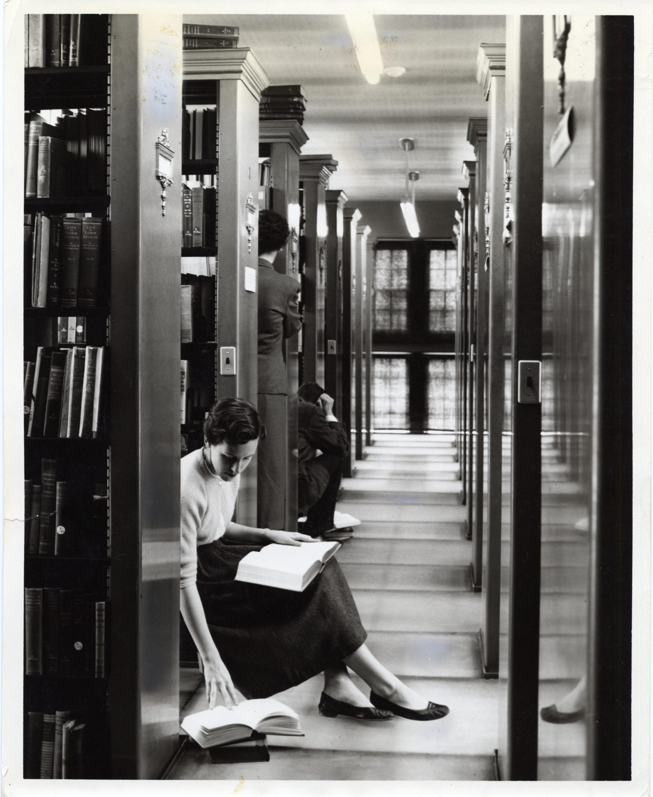 Photograph of students in between book stacks in Starr Library, in or around 1962