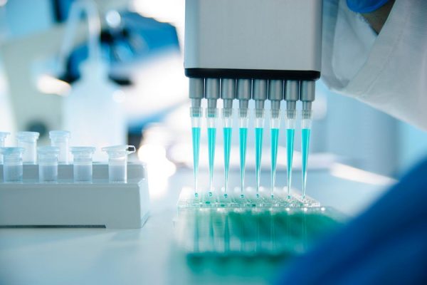 A mechanized dropper fills several vials at a time in a medical lab