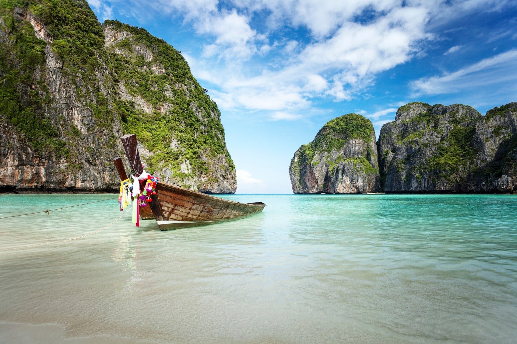 An empty boat at a tropical shore between two rocky masse