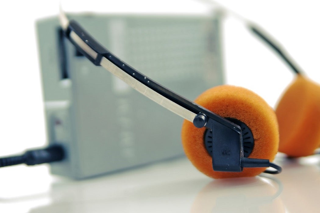 Headphones sit next to an older personal listening device.