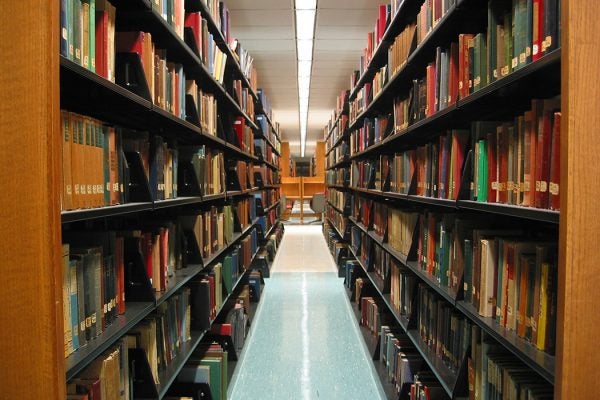 Perspective of peering down a library aisle full of books on either side