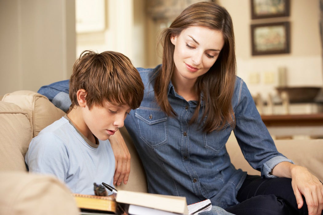 A student learns at home with a caretaker close at hand