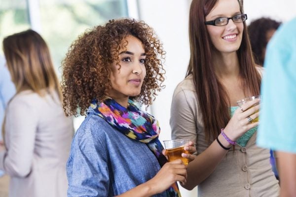 Two students look on while holding drinks