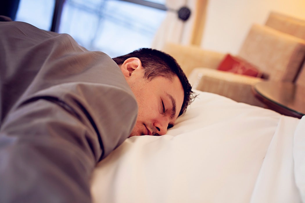 Man in work clothes sleeping on a made bed