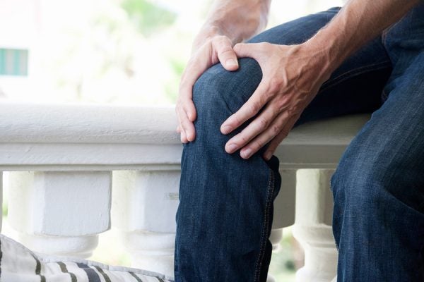 A seated individual clutching their knee