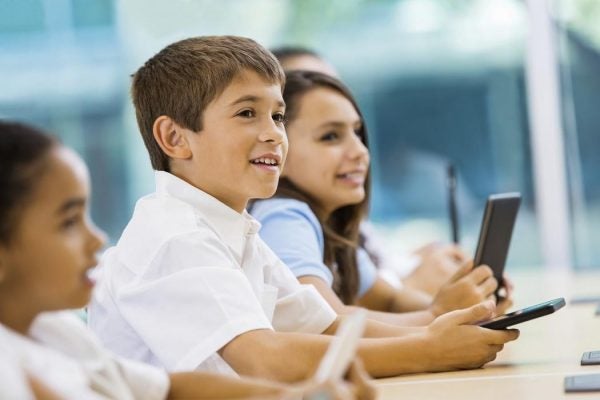 Students looking happily up from smart phones and tablets