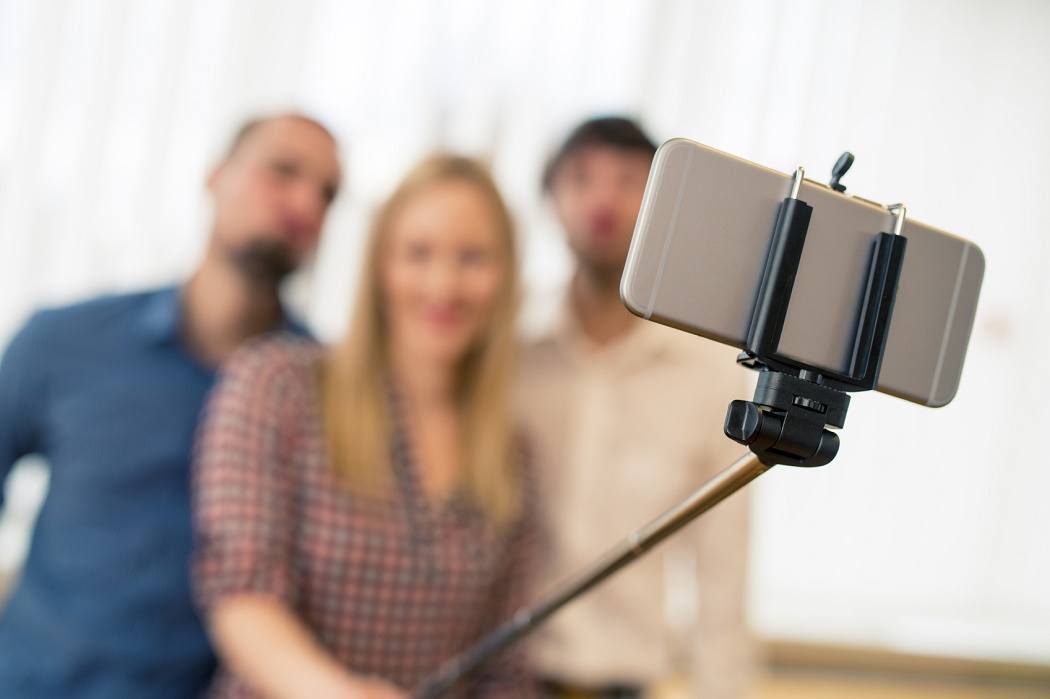 Three blurred figures taking a photo with a selfie stick