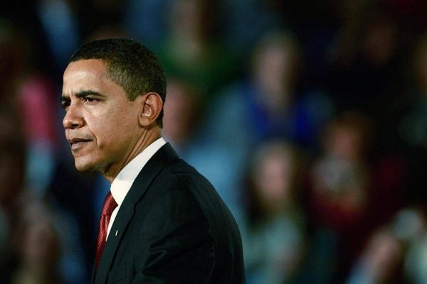 Barack Obama in the foreground with a blurred audience in the background