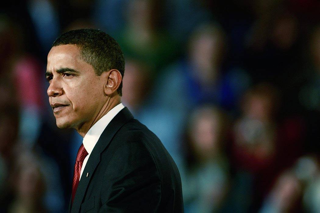 Barack Obama in the foreground with a blurred audience in the background