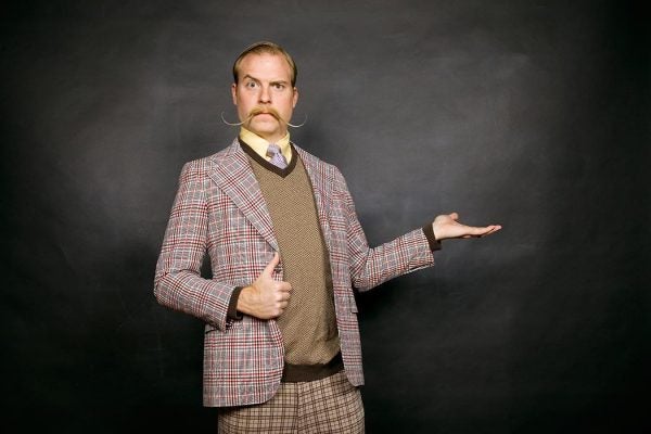 A man in mismatched plaids with a handlebar mustache