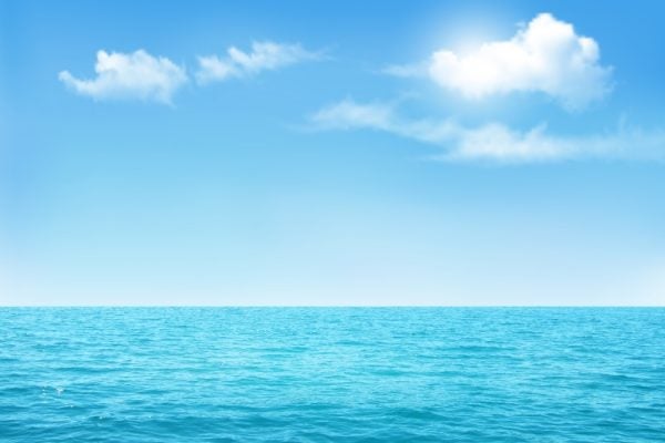 A blue ocean below an almost cloudless sky