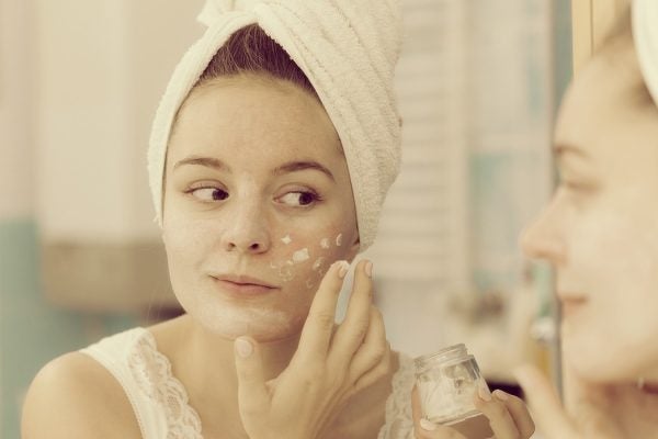 Photograph: a woman applying facial cosmetic product.