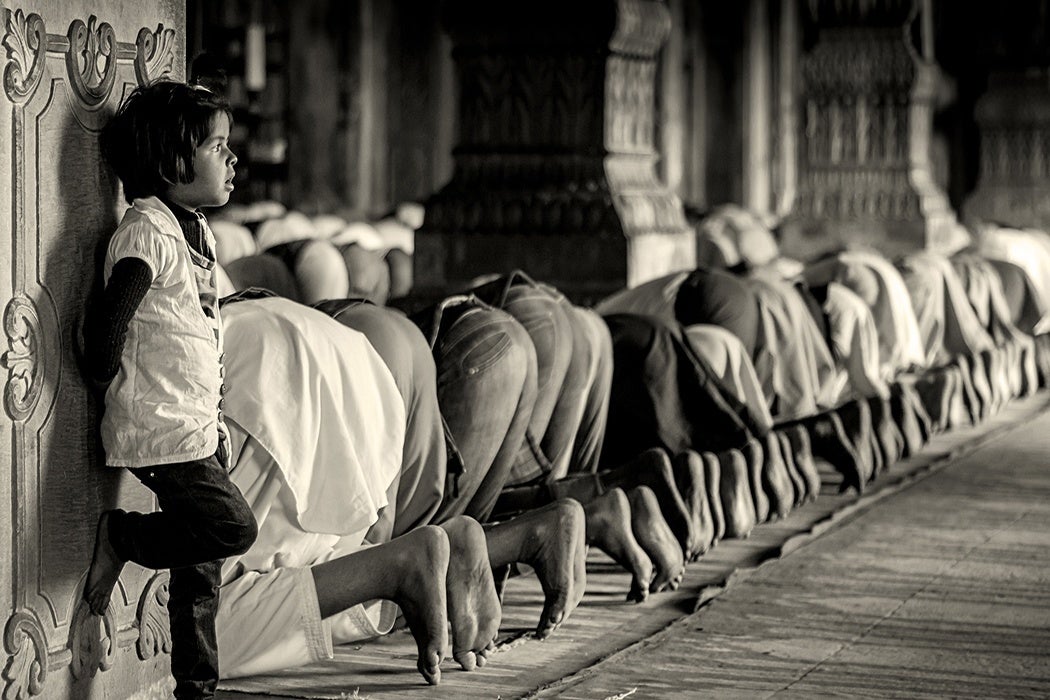 People praying during Ramadan while a while stands close by