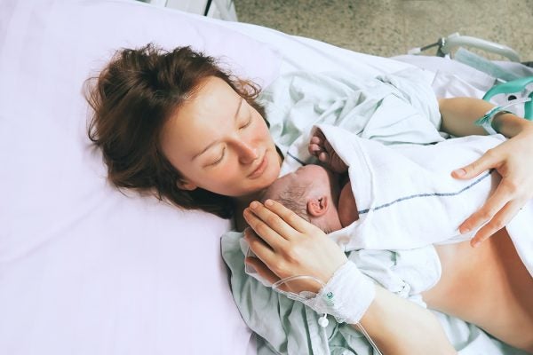 Mother holding her newborn baby child after labor in a hospital.