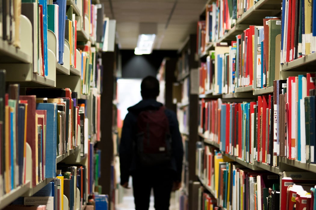 A person standing between bookshelves in a university library.