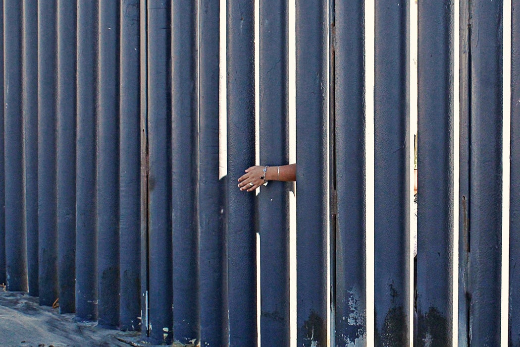 A woman's hand against a border wall