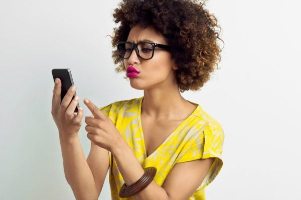 A woman looking annoyed with something on her smartphone