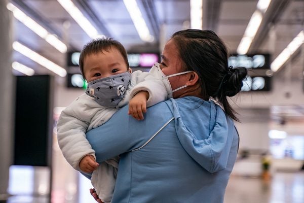 A woman carries a baby wearing a protective mask as they exit the arrival hall at Hong Kong High Speed Rail Station on January 29, 2020 in Hong Kong, China.