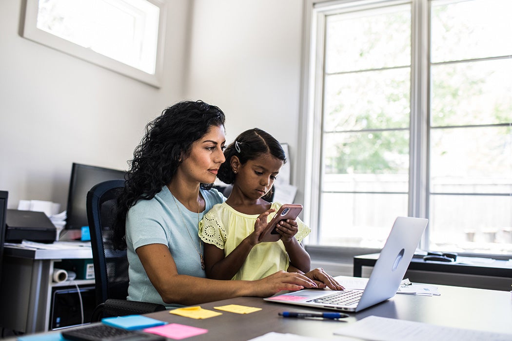 Daughter sitting in working mothers lap