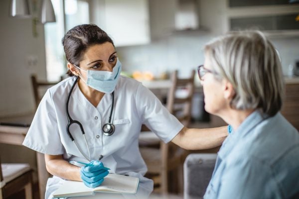 A healthcare worker reassures a patient during a home visit