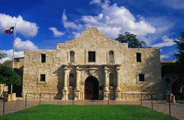 The Alamo by day with the Texas flag waving