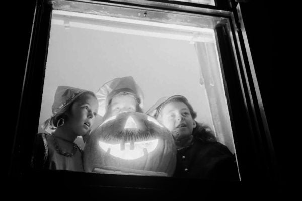 Three costumed girls, Pauline, Barbara and Dorothy Luck surrounding Halloween pumpkin, 1940