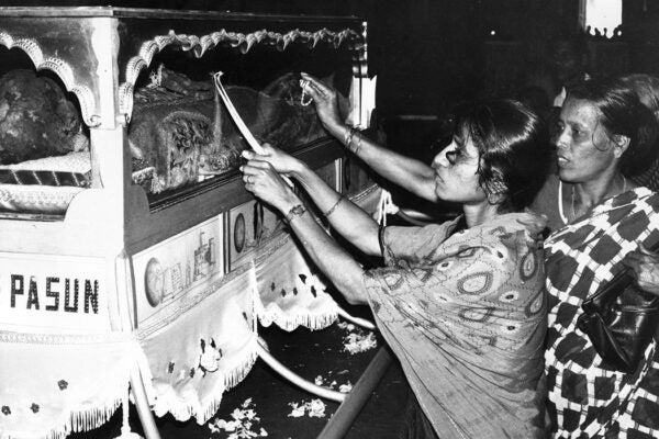 Pilgrims raising candles to the glass tomb cover of St. Francis Xavier in the Basilica of Dom Jesus, Goa, India, 1974