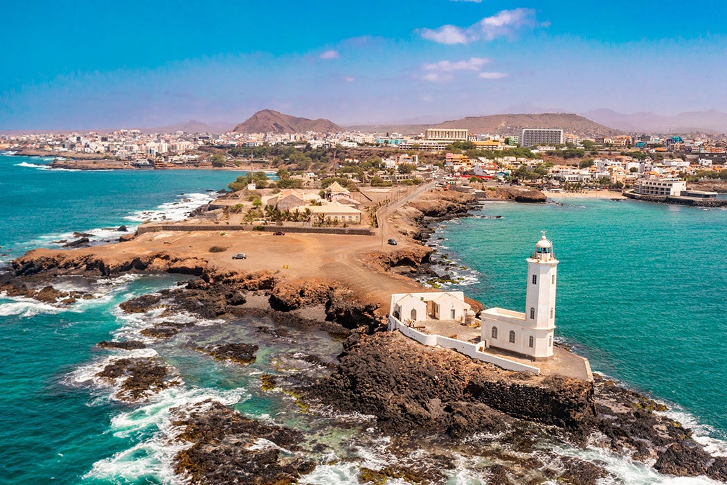 An aerial view of the shore of Praia de Santiago and the Praia lighthouse on a sunny day