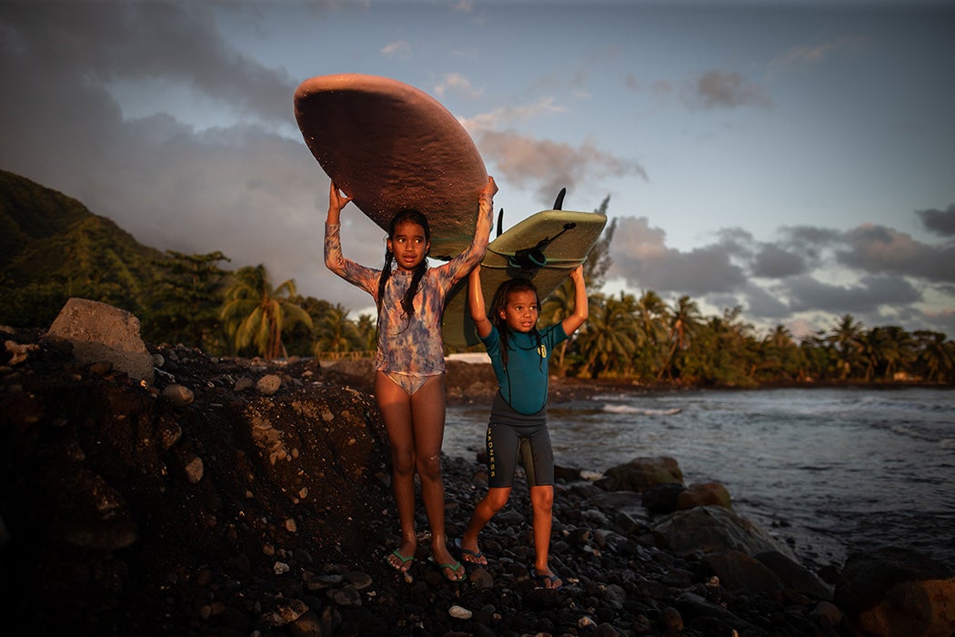 Children walk with their surfboards after surfing in Teahupo'o Bay on August 17, 2023 in Teahupo'o, French Polynesia.