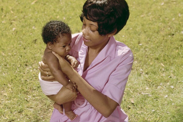 A young woman sits on the grass with her baby, USA, circa 1975