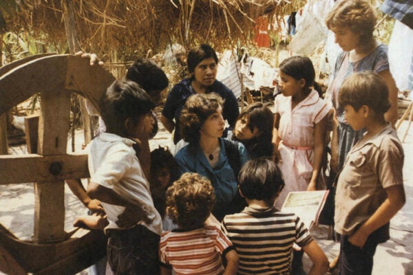 Mary Kay Baum shares photos and drawings with children at the Tres Cabelas cooperative school, 1986