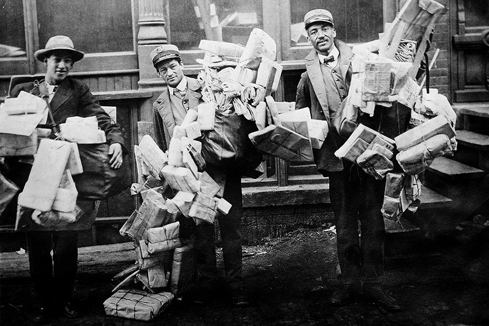 Three men loaded with Christmas mail, circa 1910 