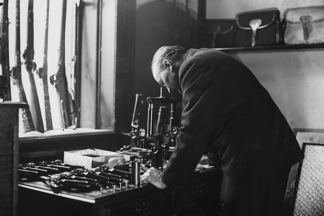 Gunsmith and ballistics expert Robert Churchill using a microscope to help compile a ballistic report for Scotland Yard in the case of the murder of Essex police officer PC George Gutteridge, 1927