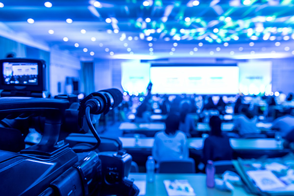 The view from the back of a conference room. The room is lit with blue lights.