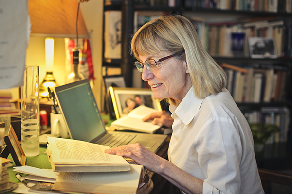 A woman reads from a book on her left and keeps her place in another book on her right.