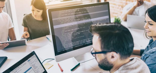 team sitting at a desk looking at a computer screen