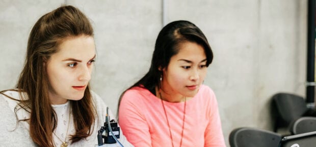 two women working at a computer desk