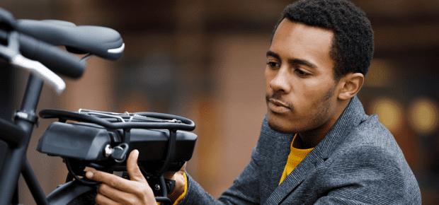 Young man changing battery pack on electric bicycle