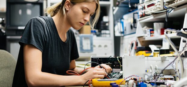 Young female engineer measuring voltage on a conductor board in her workshop