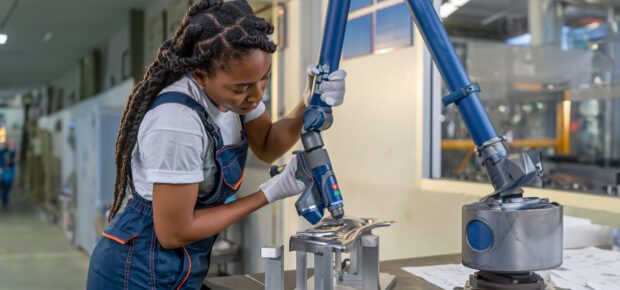 Female automation engineer wear a blue uniform with helmet safety inspection control a robot arm welding machine