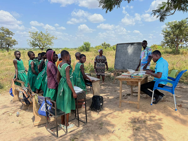 Students and teacher having class outside in Africa.